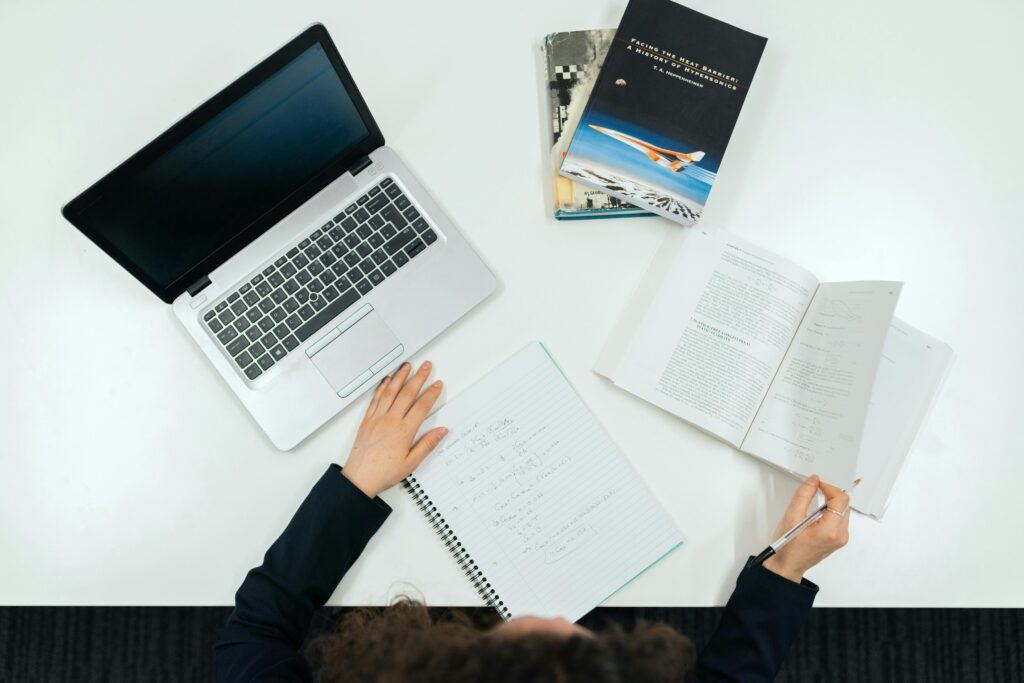 Top view of a work desk with laptop, books, and notes showcasing productivity.